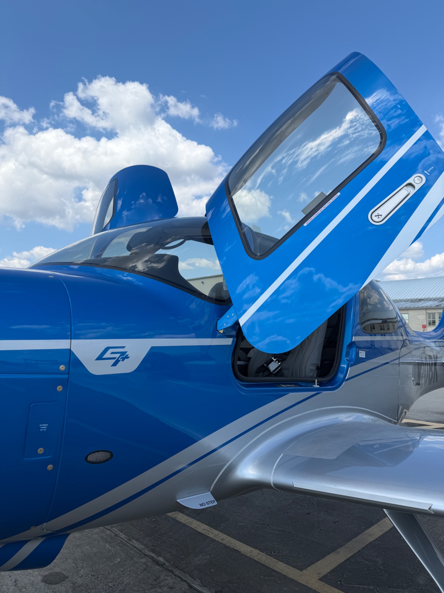 Open cabin door and polished blue fuselage of a Cirrus SR-series aircraft